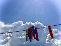 in geroplatanos a clothes line with colorful chlothes pins ist hanging in front of a shiny blue sky with somes clowds