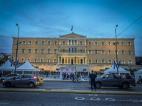 the illuminated greek parliament at the synthagma in athens with traffic in front at an evening light