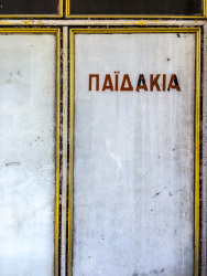 in diakopto on a white glassdoor with golden edges of an old shop ist written paidakia