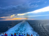 ferry traveler are looking in wake, in sky and in the sunset on the adria between italy and greece