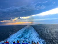 ferry traveler are looking in wake, in sky and in the sunset on the adria between italy and greece