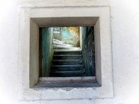 through an open window you see blue stairs and a lighty window in eleousa on rhodes