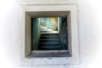 through an open window you see blue stairs and a lighty window in eleousa on rhodes