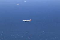 with the aegean sea in the background there are two ferries, one airplane and many surfer in the distance