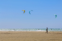 a woman is walking at the beach in prasonisi on rhodes and pasts kitesurfers there