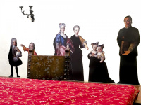 behind a table with a red tablecloth and a historical chair are colorful figures of the time of the dukes in the diocesan museum in bovino in puglia