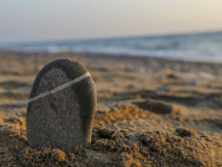 an upright grey stone in the sandy limni beach on rhodes with the ocean behind and sunsetlight