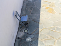 in the courtyard of the church kimisis theotokou in asklipio on rhodes is standing a blue wooden chair in the shadow on a stone floor