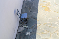 in the courtyard of the church kimisis theotokou in asklipio on rhodes is standing a blue wooden chair in the shadow on a stone floor