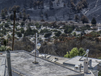 an air conditioner on top of houses in asklipio on rhodes are standing in front of the burned landscape around the village