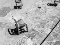 various chairs are standing in the courtyard of the church kimisis theotokou in asklipio on rhodes, black-and-white