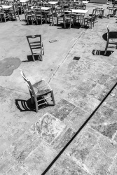 various chairs are standing in the courtyard of the church kimisis theotokou in asklipio on rhodes, black-and-white