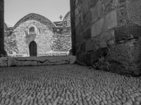 a path of cobblestones lead to the church kimisis theotokou in asklipio on rhodes, black-and-white