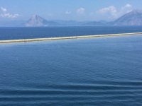 waves in front of the sea in patras, hills in the background and a quay between the scene