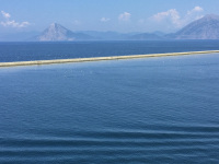 waves in front of the sea in patras, hills in the background and a quay between the scene