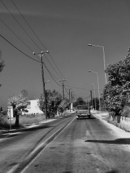 an old toyota pickup is driving on a street near kalavarda on rhodes along old electricity pylons, black-and-white