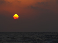 the sun is going down like a orange ball in the sea at limni beach on rhodes