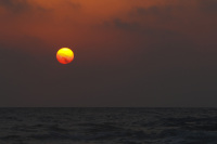 the sun is going down like a orange ball in the sea at limni beach on rhodes