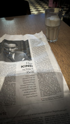 the newspaper \"Die Welt\" with an article about Klaus Mann an a glass of latte macchiato on a table at the swiss lounge at the airport in zurich