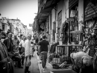 a group of men are standing in front of a shop with many flea market items in monastiraki in athens, black-and-white