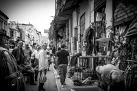 a group of men are standing in front of a shop with many flea market items in monastiraki in athens, black-and-white