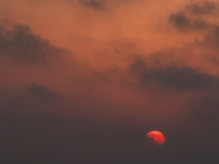 a red sky with dark clowds and the going down sun like a red ball at limni beach on rhodes
