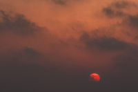 a red sky with dark clowds and the going down sun like a red ball at limni beach on rhodes