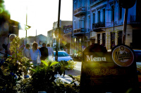 behind a menu sign of the restaurant dipilo in monastiraki in athens pedestrian are going in the backlight