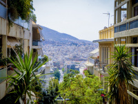 palms and houses with balcons at the sides with a view from the path from lycabettus in athens downstairs to the train station