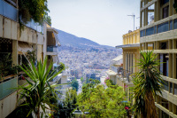 palms and houses with balcons at the sides with a view from the path from lycabettus in athens downstairs to the train station