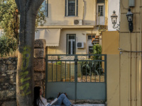 a girl is reading a book in front of an old door in plaka in athens