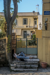 a girl is reading a book in front of an old door in plaka in athens