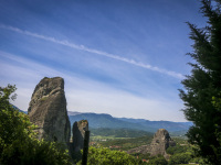 a big contrail at the blue sky behind a mystic hill in meteora in greece