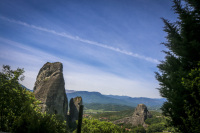 a big contrail at the blue sky behind a mystic hill in meteora in greece