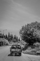 an old pickup is driving on an old road near trikala in greece, black-and-white