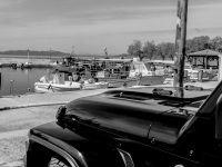 the front of a sahara jeep unlimited is standing at the harbor of arkitsa, black-and-white