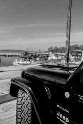 the front of a sahara jeep unlimited is standing at the harbor of arkitsa, black-and-white