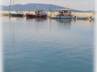 the turquoise sea at the harbor in arkitsa with some boats in the background