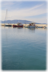 the turquoise sea at the harbor in arkitsa with some boats in the background