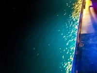 while a nightly trip to rhodes there is a illuminated shiprailing and the turquoise sea