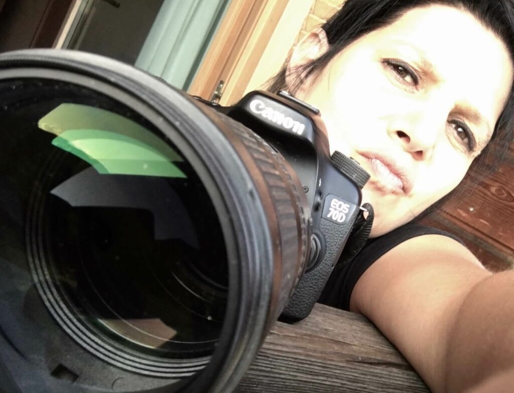 FOTO MAU - VITA Selbstportrait der Fotografin Marina Alexiou. Sie schaut in die Ferne und hält ihre Canon EOS 70D bereit zum Fotografieren. Vom Fotografenhandwerk bis zur Pressearbeit